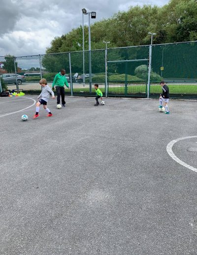 Kids play football on outdoor pitch