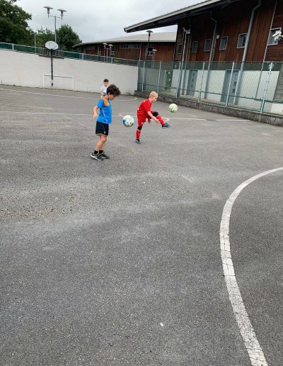 Kids play football on outdoor pitch