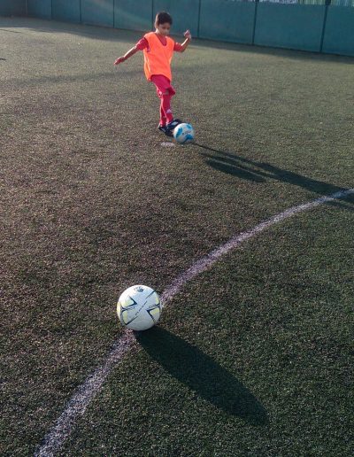 Kids play football on outdoor pitch