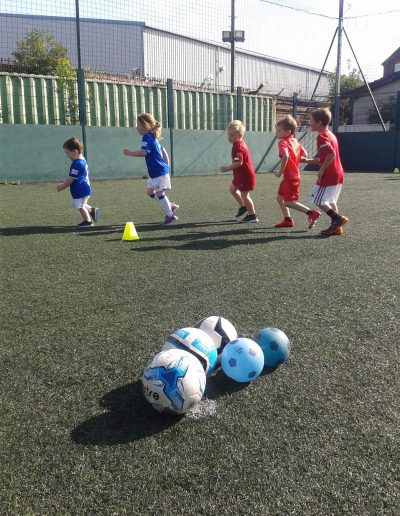 Kids play football on outdoor pitch